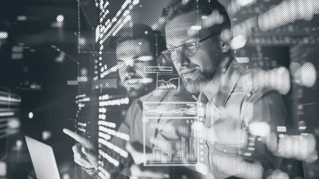Two engineers at work behind a screen of code
