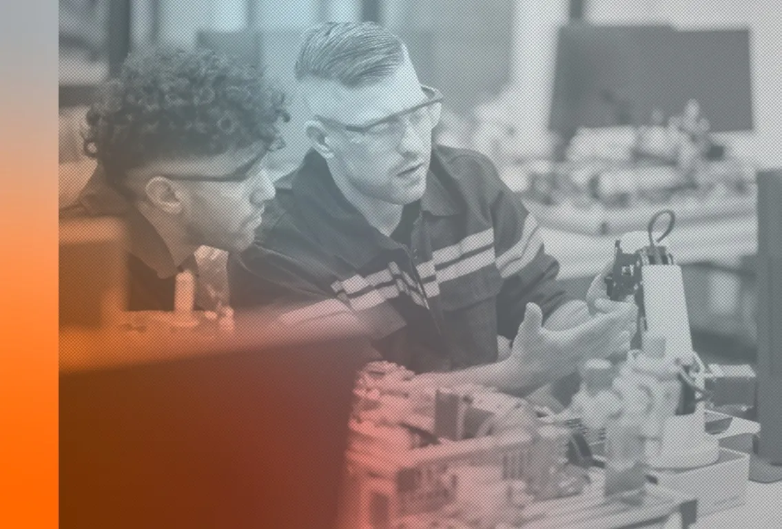 Two engineers reviewing a robotic assembly on a workbench